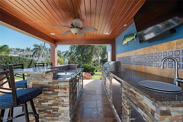 view of patio featuring ceiling fan, area for grilling, and a wet bar