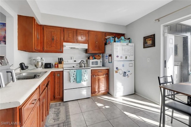 kitchen with light tile patterned floors, white appliances, washer / clothes dryer, and sink