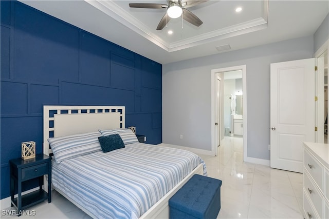 bedroom with connected bathroom, a tray ceiling, ornamental molding, and ceiling fan