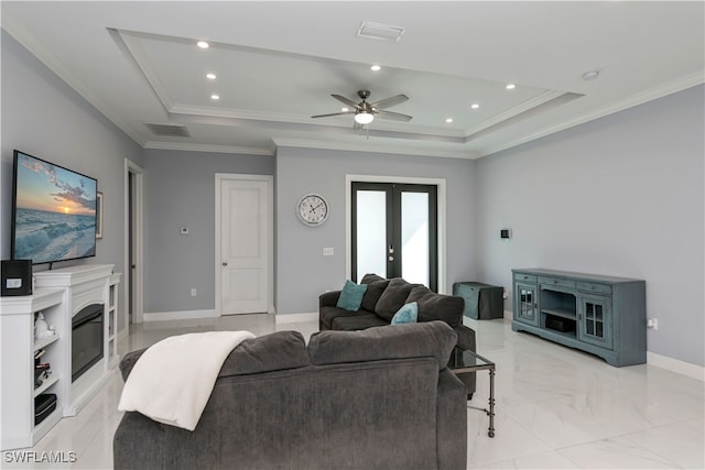 living room featuring a raised ceiling, ornamental molding, ceiling fan, and french doors