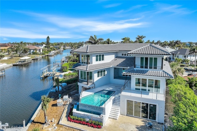 back of property with a water view, a balcony, and a patio