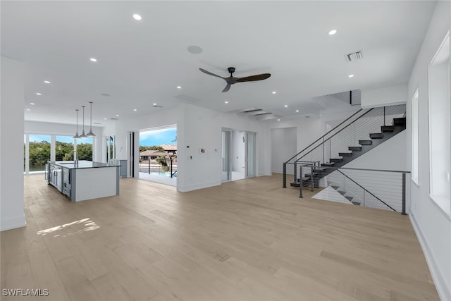 unfurnished living room with ceiling fan, sink, and light wood-type flooring