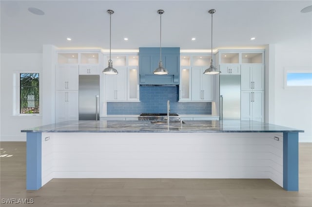 kitchen featuring built in refrigerator, white cabinetry, and dark stone countertops