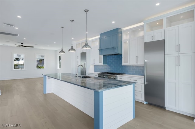 kitchen featuring pendant lighting, sink, appliances with stainless steel finishes, white cabinetry, and an island with sink