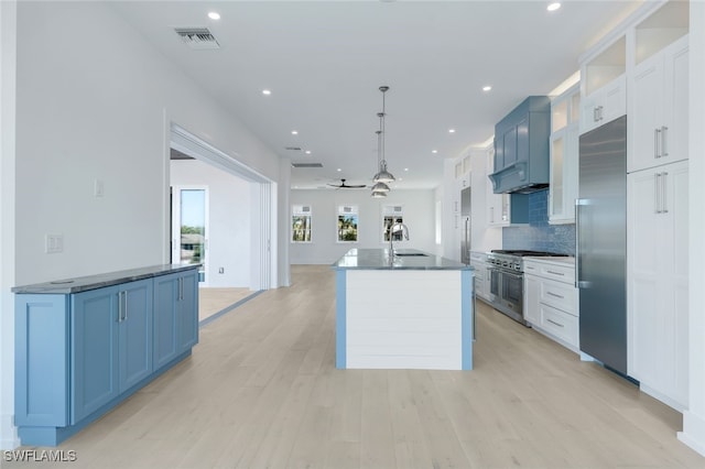 kitchen with white cabinets, blue cabinets, decorative light fixtures, and premium appliances