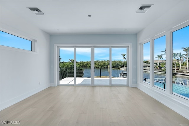 unfurnished room featuring a water view and light hardwood / wood-style flooring