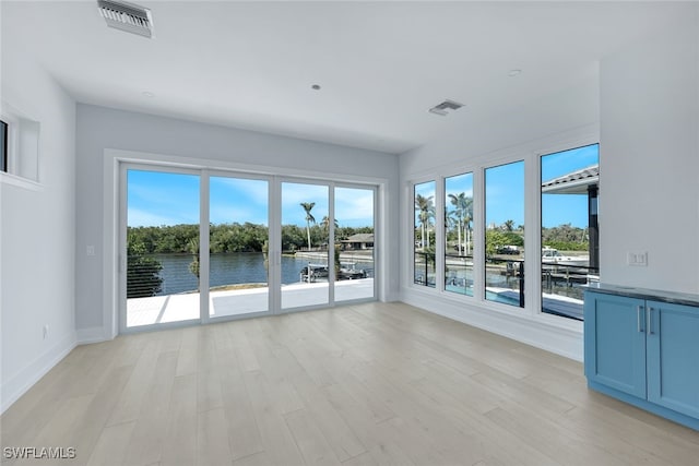 unfurnished room with a water view, plenty of natural light, and light wood-type flooring