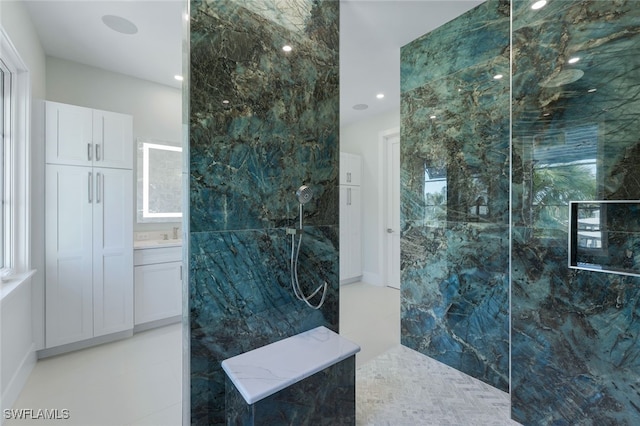 bathroom with tiled shower, vanity, and tile walls