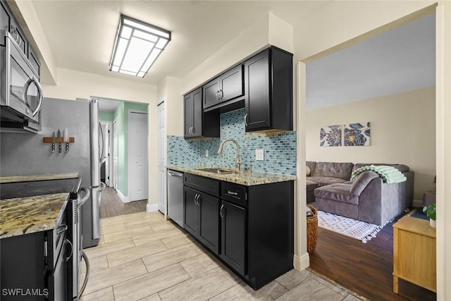 kitchen with tasteful backsplash, appliances with stainless steel finishes, sink, and light stone counters