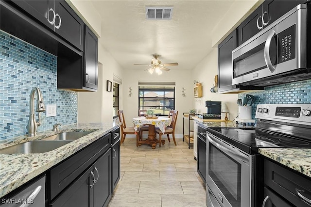 kitchen featuring ceiling fan, stainless steel appliances, light stone countertops, and sink