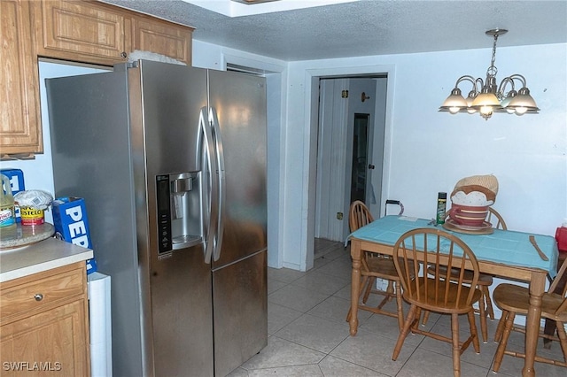 kitchen featuring light tile patterned flooring, pendant lighting, stainless steel fridge, a chandelier, and a textured ceiling