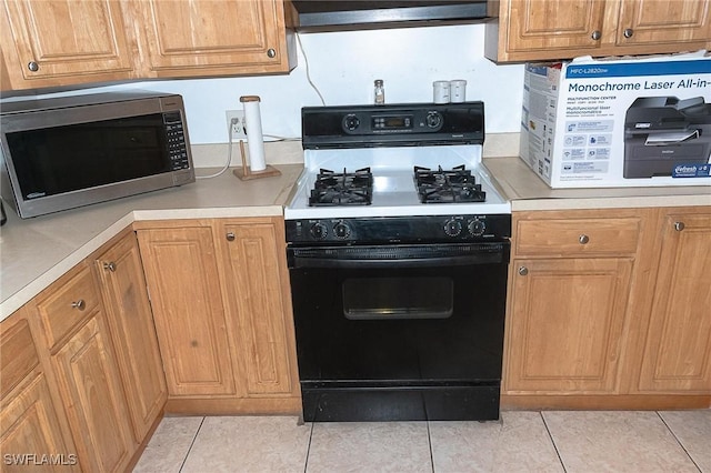 15323 E State Road 78, Okeechobee, FL 34974 - kitchen with light countertops, stainless steel microwave, gas range oven, light tile patterned flooring, and extractor fan