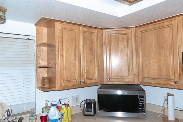 15323 E State Road 78, Okeechobee, FL 34974 - interior details featuring a textured ceiling, brown cabinets, stainless steel microwave, and open shelves