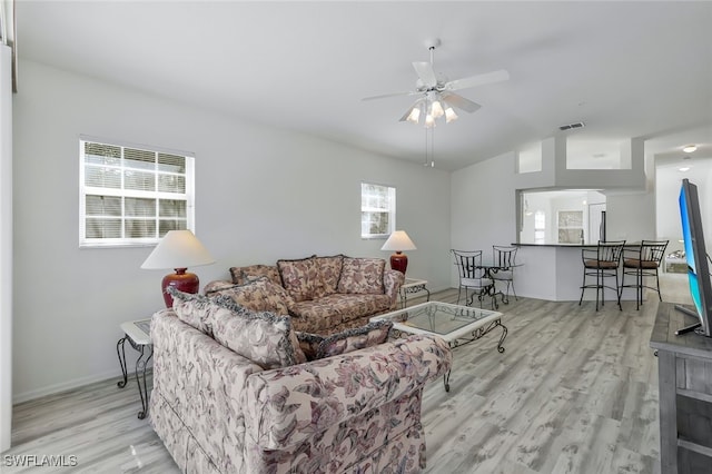 living room with ceiling fan, vaulted ceiling, and light hardwood / wood-style floors