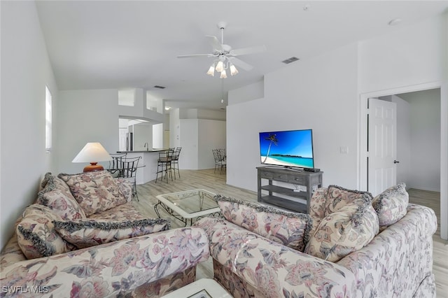 living room with ceiling fan, vaulted ceiling, and light hardwood / wood-style flooring