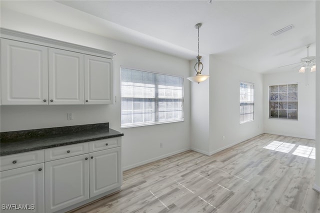 unfurnished dining area with ceiling fan and light wood-type flooring