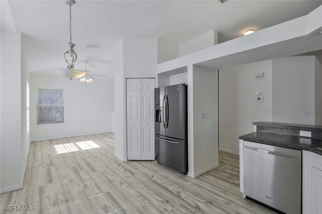 kitchen with hanging light fixtures, appliances with stainless steel finishes, white cabinets, and light wood-type flooring