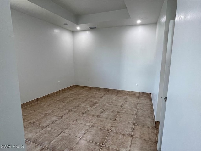 spare room featuring light tile patterned floors and a tray ceiling