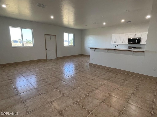 unfurnished living room with sink and light tile patterned floors