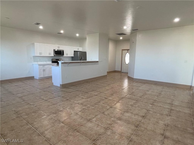 kitchen with a breakfast bar, kitchen peninsula, white cabinets, and appliances with stainless steel finishes