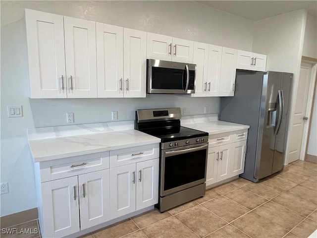 kitchen featuring white cabinetry, stainless steel appliances, light stone counters, and light tile patterned floors