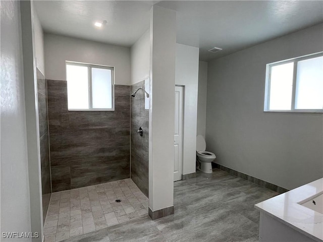 bathroom with vanity, toilet, and a tile shower