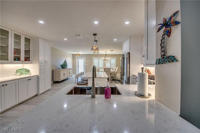 kitchen featuring pendant lighting, high end refrigerator, sink, and white cabinets