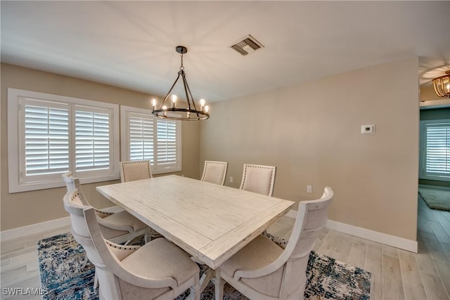 dining space featuring a notable chandelier and light wood-type flooring