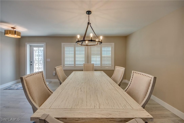 dining room with light wood-type flooring and a notable chandelier