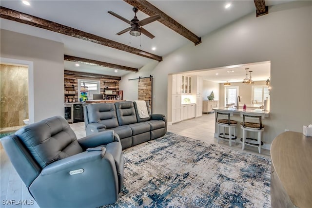 living room with light hardwood / wood-style flooring, ceiling fan, a barn door, beverage cooler, and beamed ceiling