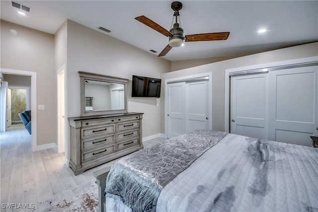 bedroom with multiple closets, ceiling fan, vaulted ceiling, and light wood-type flooring