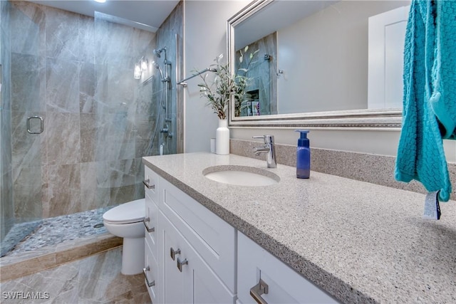 bathroom with vanity, a shower with door, and toilet