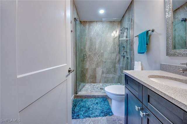 bathroom featuring a shower with door, vanity, and toilet