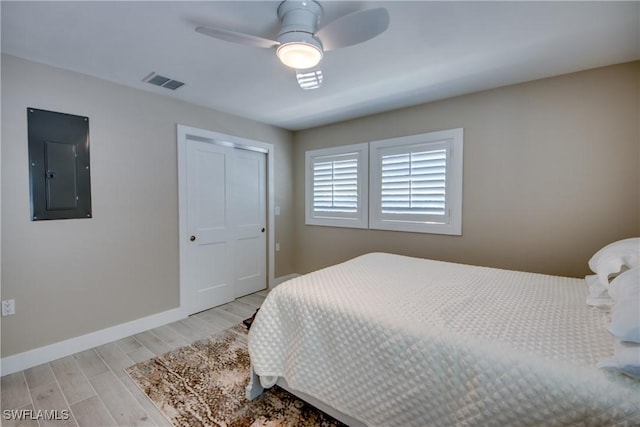 bedroom featuring light hardwood / wood-style flooring, electric panel, a closet, and ceiling fan