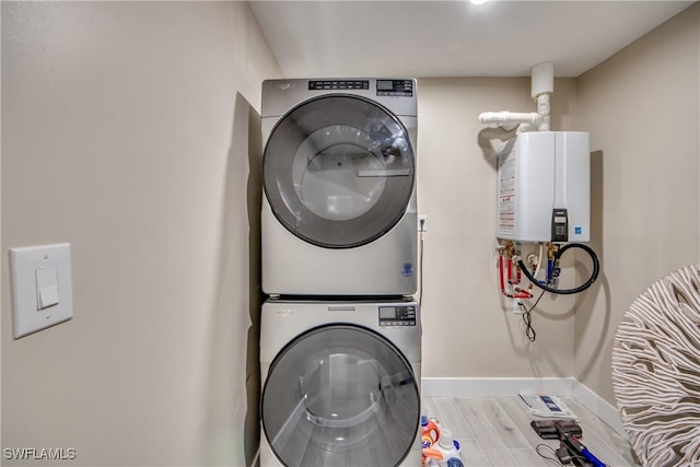 clothes washing area with stacked washer and clothes dryer, light hardwood / wood-style floors, and water heater