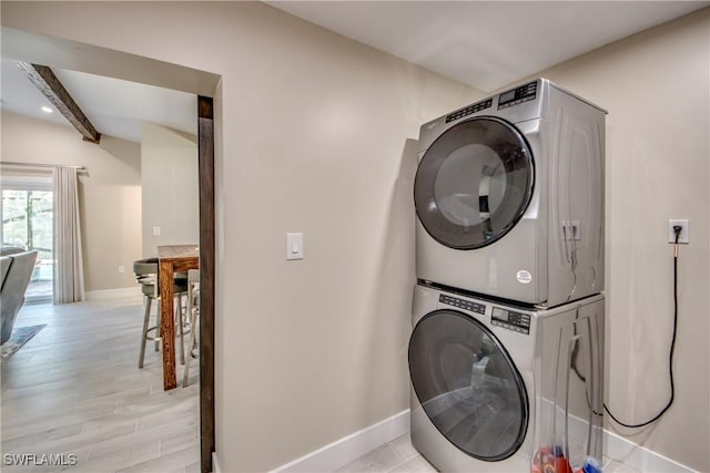 clothes washing area featuring light hardwood / wood-style floors and stacked washing maching and dryer