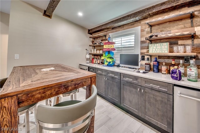 kitchen with dark brown cabinetry, beam ceiling, light wood-type flooring, and wood walls