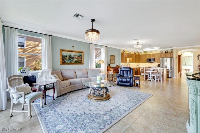 tiled living room with ornamental molding and a notable chandelier