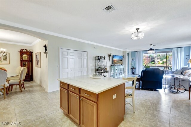 kitchen featuring hanging light fixtures, ornamental molding, a kitchen island, and light tile patterned floors