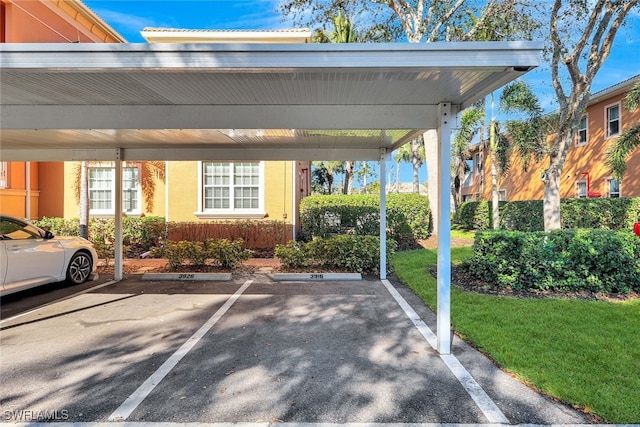 view of parking / parking lot featuring a yard and a carport