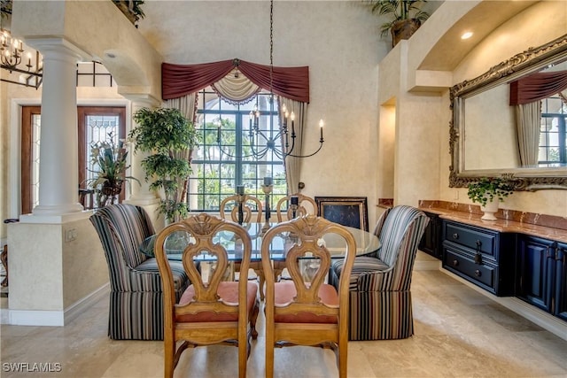 dining space with a towering ceiling, a chandelier, and ornate columns