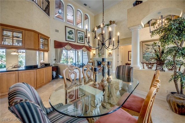 dining area with decorative columns, crown molding, and a notable chandelier