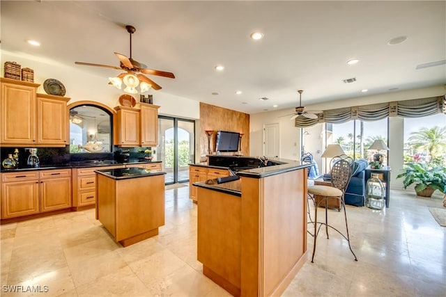 kitchen with tasteful backsplash, decorative light fixtures, ceiling fan, and a kitchen island