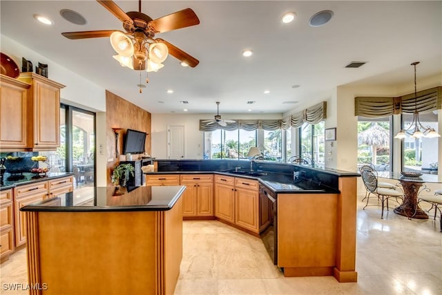 kitchen with hanging light fixtures, black dishwasher, a kitchen island with sink, and sink