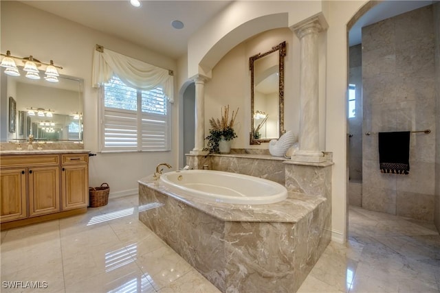 bathroom featuring decorative columns, vanity, and tiled bath