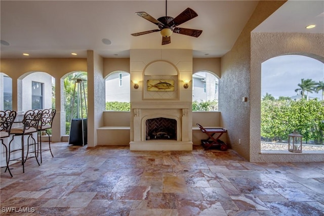 unfurnished living room with ceiling fan and a fireplace