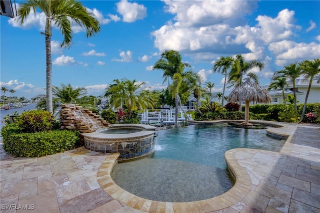 view of swimming pool featuring an in ground hot tub, a water view, and a patio area