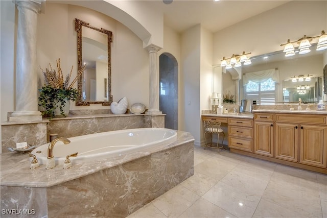 bathroom featuring a relaxing tiled tub, vanity, and ornate columns