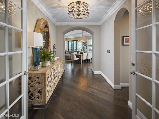 hallway with french doors, ornamental molding, dark hardwood / wood-style flooring, and a notable chandelier