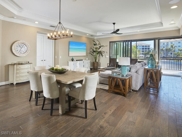 dining space with dark hardwood / wood-style floors, a tray ceiling, ceiling fan with notable chandelier, and crown molding